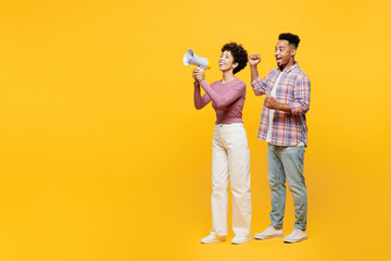 Full body young couple two friends family man woman of African American ethnicity wear purple casual clothes together hold megaphone scream announces sale Hurry up isolated on plain yellow background.