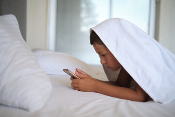 Youngster engrossed in smartphone, comfort of home. Highlights modern solitude in the digital age,...