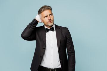 Adult confused sad barista male waiter butler man wear shirt black suit bow tie elegant uniform look aside hold scratch head work at cafe isolated on plain blue background Restaurant employee concept