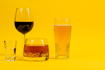 glasses filled with different types of alcohol, beer, wine, whiskey, vodka in glasses on a yellow background
