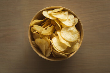Close-up of potato chips or crisps in a bowl on a wooden background