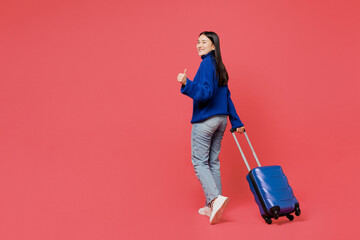 Happy traveler woman wears blue sweater casual clothes hold bag walk isolated on plain pastel pink background. Tourist travel abroad in free spare time rest getaway. Air flight trip journey concept..