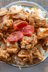 top view bowl of rice with pork ribs and slices of Chinese style sausage at vertical composition