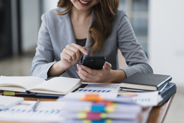 Accounting asian woman use smartphone and laptop at office desk in office, Accounting businesswoman online working concept.