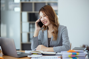 Accounting asian woman use smartphone and laptop at office desk in office, Accounting businesswoman online working concept.