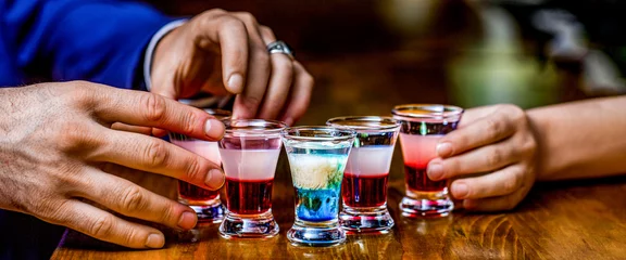 Fotobehang Man hands glasses of shot or liqueur. Glasses of alcohol. Tequila shots, vodka, whisky, rum. Group friends tequila shot glasses in bar © Yevhen