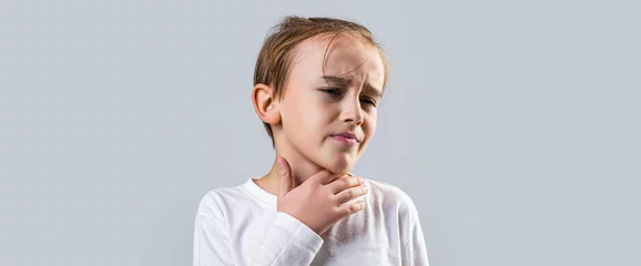 Fotobehang Ill little boy with sore throat. Ill child with sore throat. Sore throats in a child. Child has a sore throats. Signs of a cold in children. Young boy feels that his throat is pain © Yevhen