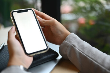 Closeup businesswoman using mobile phone at cafe. White empty screen for advertising text