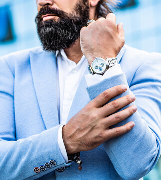 Man holds his watch. Portrait successful businessman in a business suit, using the watch. Businessman points to his watch