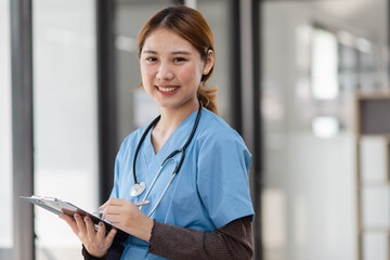 Happy asian female doctor holding a patient clipboard standing in hospital, Medicine and healthcare concept.