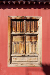 Old weathered brown wooden window on the red wall. Tenerife. Canary Island, Spain