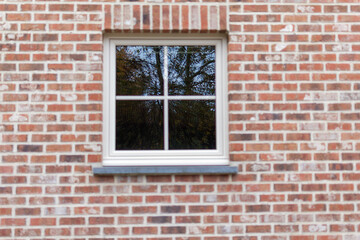 white window with reflection in the glass on a brick wall