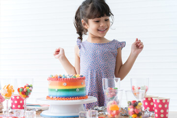 Smiling Caucasian little kid girl in cute dress, surprised and excited on birthday party, looking...