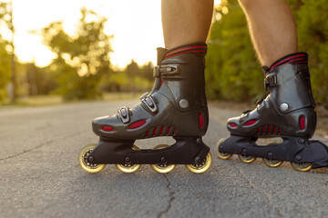 unrecognizable feet with rolling skate close up on rural paved street with sun flare or back light low angle view