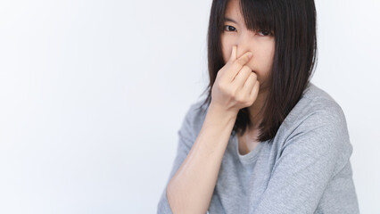 Asian woman covers her nose because she smells a bad smell.