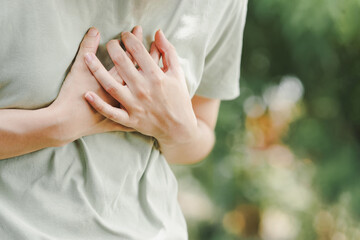 Close-up of women hand held his chest in pain. Concept of heart disease. - obrazy, fototapety, plakaty