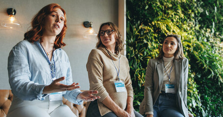 Female professionals engaged in productive discussion at a business conference - obrazy, fototapety, plakaty