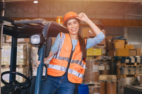 Happy asian female young worker works in port cargo shipping logistic transport industry enjoy smiling working operate forklift driver.