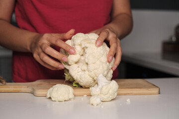 Soft fingers crack open a vibrant bounty of cauliflower. Step into the realm of conscious eating, making every meal a mindful choice.