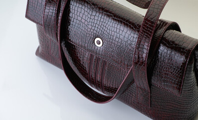 Close-up of a fashionable brown crocodile leather women's handbag on white background