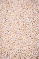 White uncooked rice in a round ceramic bowl on a dark concrete background