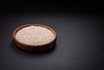 White uncooked rice in a round ceramic bowl on a dark concrete background