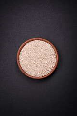 White uncooked rice in a round ceramic bowl on a dark concrete background