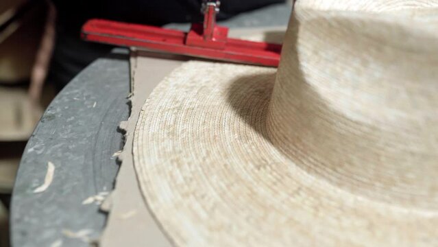 Close up measuring the brim of a traditional natural fiber hat
