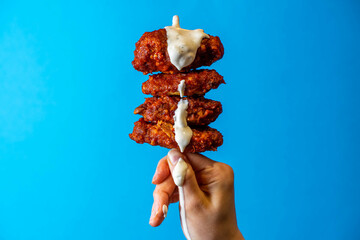 Fried Chicken Hot Wing Being Dipping With Cool Ranch Sauce, Royal Blue Background, Editorial...