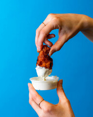 Fried Chicken Hot Wing Being Dipped Into Cool Ranch Sauce, Royal Blue Background, Editorial...