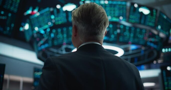Portrait of a Middle Aged Man Working on the Floor in a Modern Stock Exchange Firm. Specialist Monitoring Companies and Funds, Securities, Derivatives, Investment Products, Bonds on Computer Displays