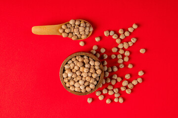 Chickpeas source of natural protein in wooden cup and spoon wooden on red background