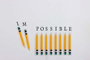 Pencils with the text impossible, stopping the domino effect. success and challenge concept
