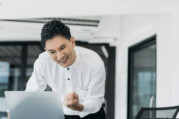 Young asian businessman are excited business success with inspiration from their excellent financial results that are happy working in a modern office on a computer.