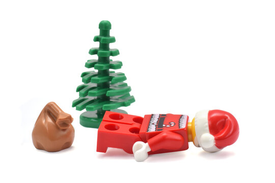 Lego minifigure of tired Santa Claus is laying under the tree isolated on white. Editorial illustrative image of popular plastic toy constructor.