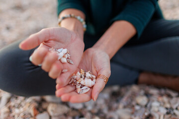 rest and meditation. a girl sits on the beach and pours shells in her hands.