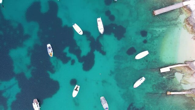 Aerial top down view to small white boats in turquoise water of the sea. Croatia coastline life