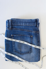 Fashion of blue jeans with measurement tape on white background with copy space.