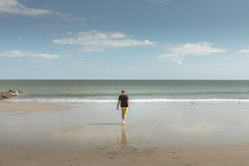 Caucasian man walking on the beach of Edisto Island, South Carolina