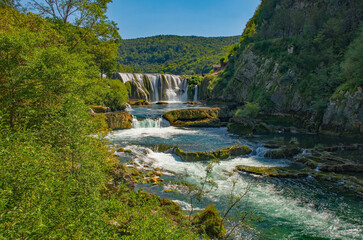 Fototapeta na wymiar Strbacki Buk, a terraced waterfall on the Una River on the border between the Federation of Bosnia and Herzegovina and Croatia. Early September