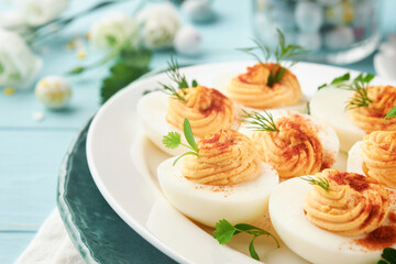Stuffed or deviled eggs with paprika and parsley on blue plate for easter table. Traditional dish for Easter. Healthy diet food for breakfast. Top view, flat lay.