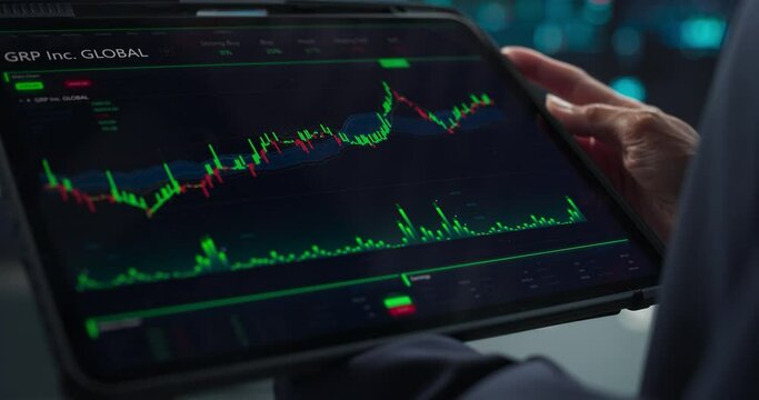 Close Up Footage of a Tablet Computer Monitor Screen with Real-Time Stocks, Commodities, Exchange Market Charts with Tickers on Display in a Financial Business Office