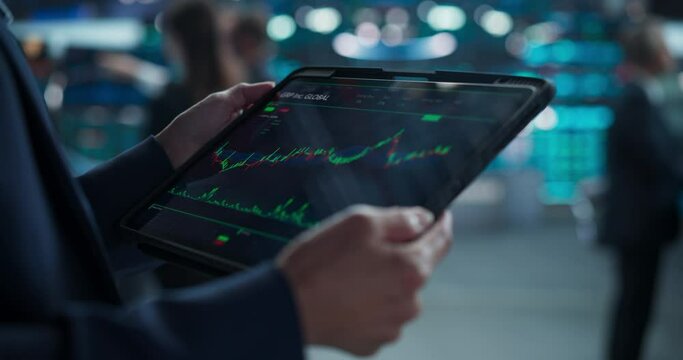 Tablet Computer Display with Real-Time Stocks, Commodities, Exchange Market Charts with Tickers. Anonymous Investment Trader Using Device in a Financial Business Office or Stock Exchange Floor