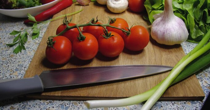  Background close-up of cherry tomatoes lying on a board next to a knife, onion, champignons, garlic and lettuce