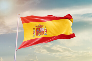 Spain national flag waving in beautiful sky. The symbol of the state on wavy silk fabric.