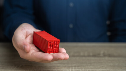 A man holds a red shipping containers in his hand. Cost savings due to bulk purchases or shared...