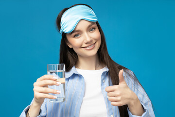 A young woman in a sleeping mask and a glass of water