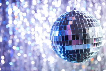Disco ball with festive silver ribbons on background