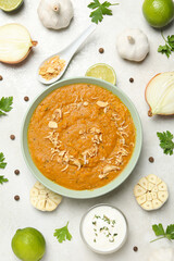 Sweet potato puree in bowl, onion, garlic and sauce on light background, top view