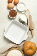 A white plate for the oven, with a pumpkin and eggs nearby.